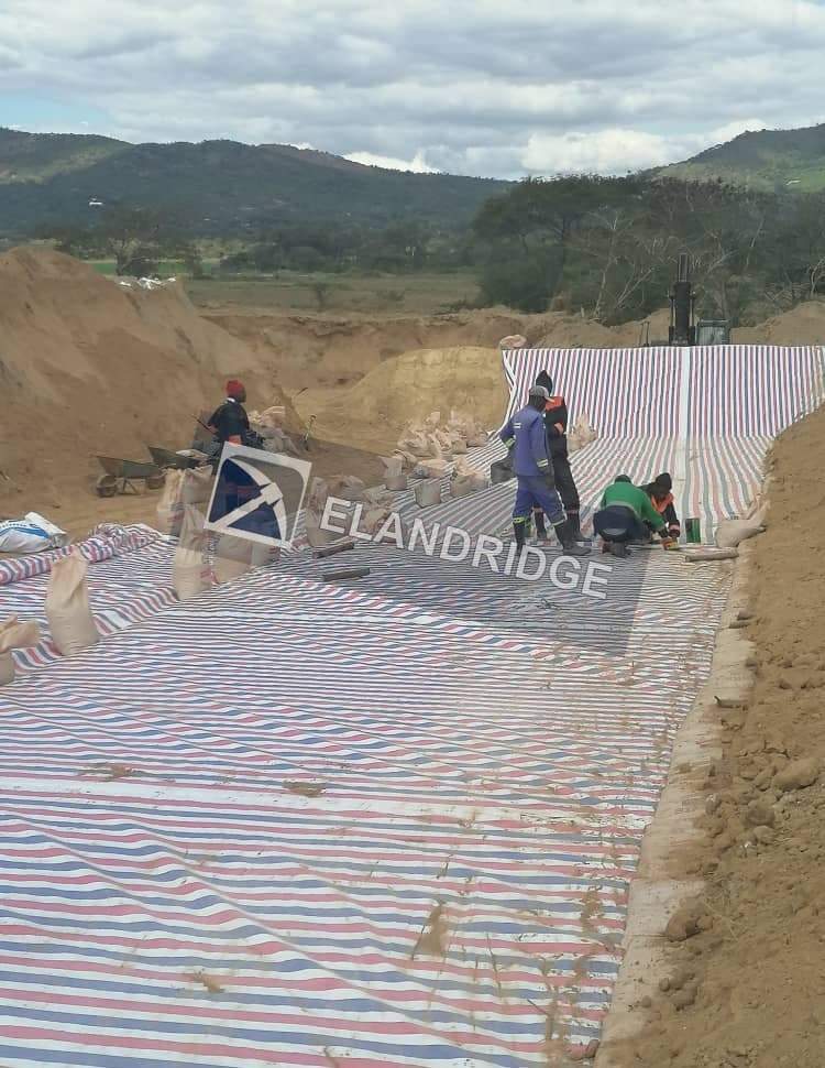 Crew installing geomembrane liner on the pad